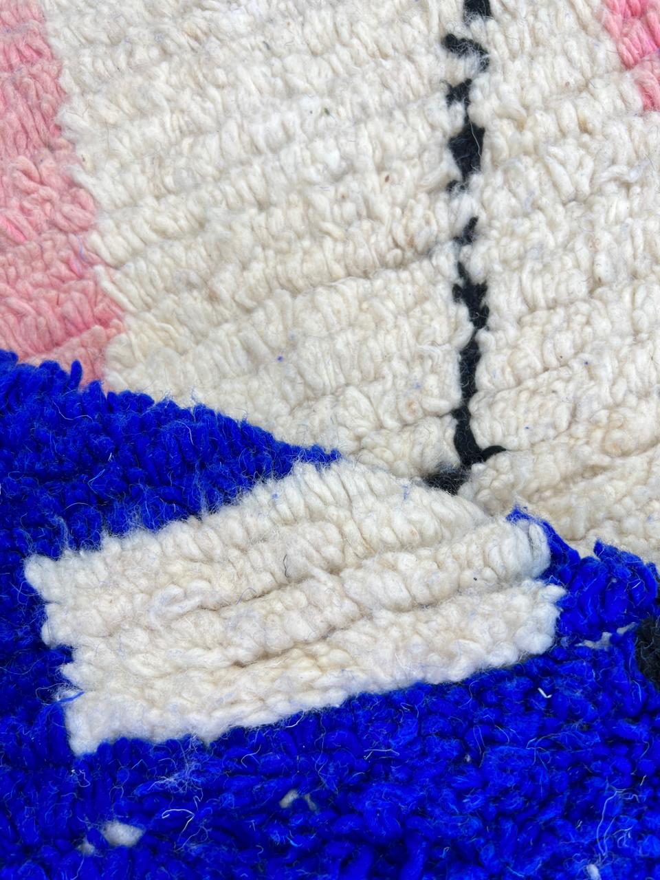 Round Moroccan wool rug with abstract blue, pink, white shapes and black line details.
