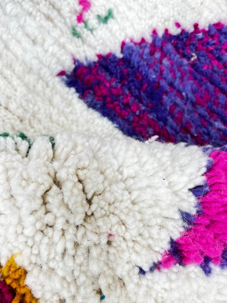 Handmade round Moroccan wool rug with colorful Berber symbols and tribal motifs on a natural white background.