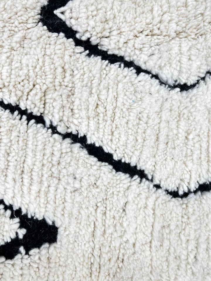 Black and white Moroccan runner rug with diamond geometric pattern made of handmade wool and black fringed ends
