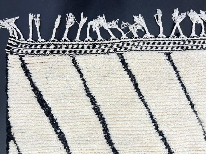 Handmade Moroccan runner rug with black geometric diamond pattern on a white wool background.