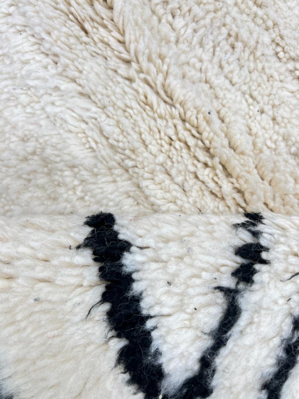 Black and white handmade Beni Ourain Moroccan wool rug with geometric diamond design and fringed edges
