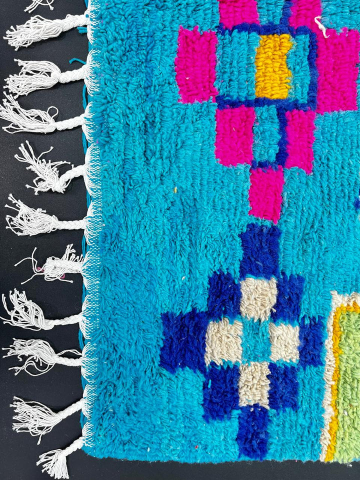 Handmade blue Moroccan wool runner rug with colorful Berber geometric motifs in orange, green, brown, navy, fuchsia, and cream