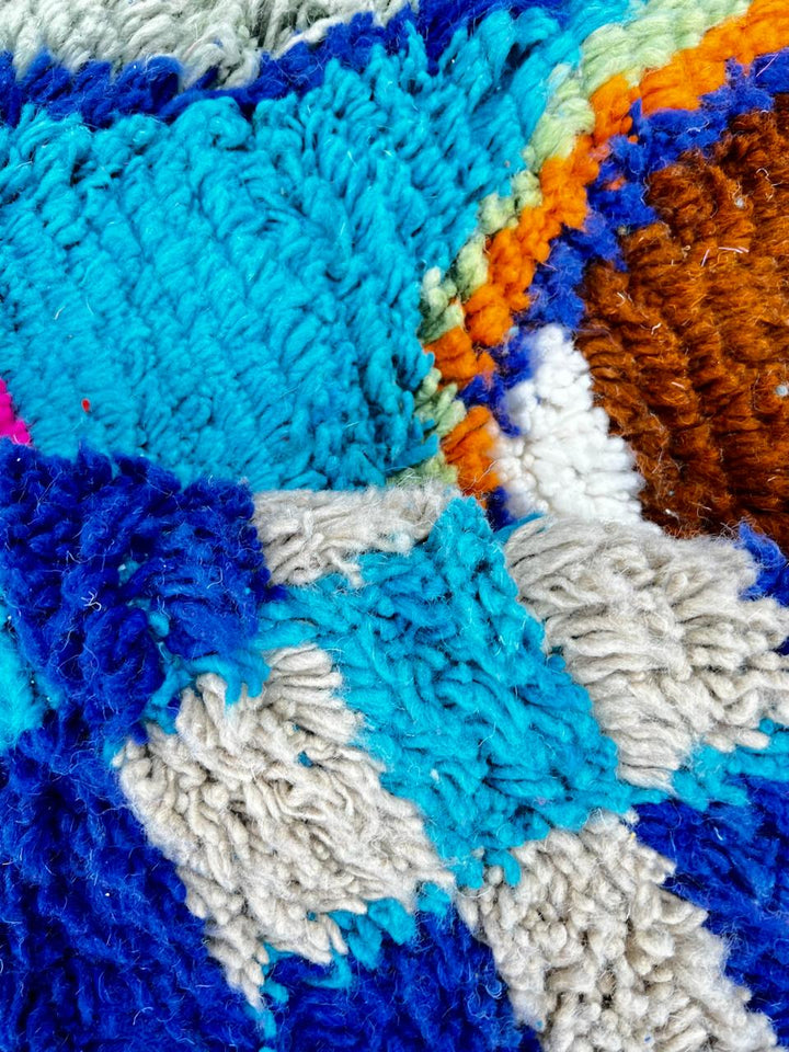 Handmade blue Moroccan wool runner rug with colorful Berber geometric motifs in orange, green, brown, navy, fuchsia, and cream