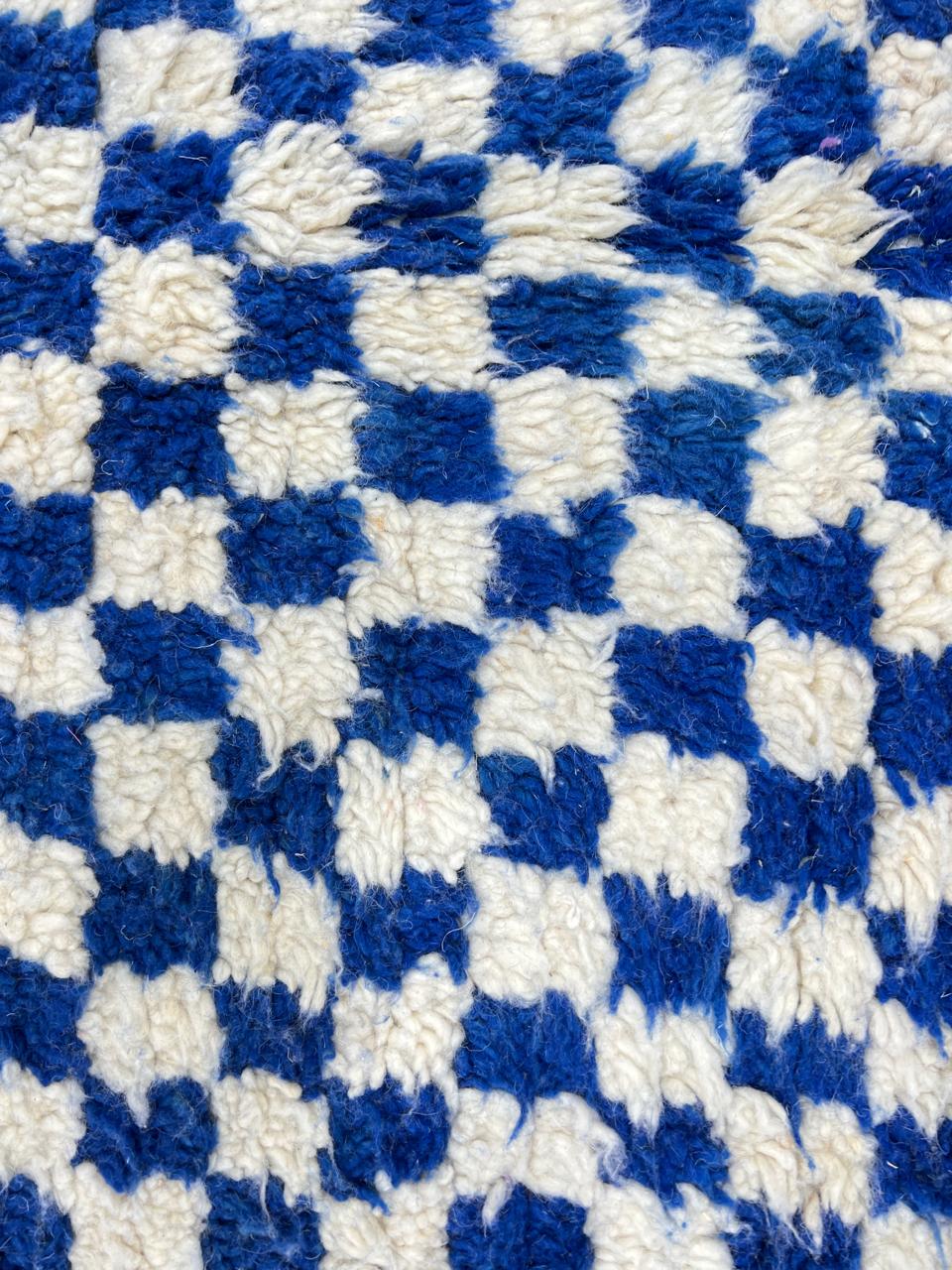 Handmade Moroccan wool rug with blue and white checkerboard pattern, round shape, and soft plush texture.