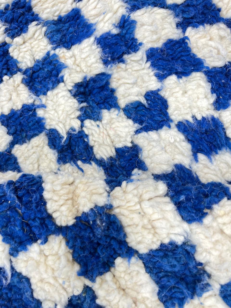 Handmade round blue and ivory Moroccan wool rug featuring a bold checkerboard geometric pattern.