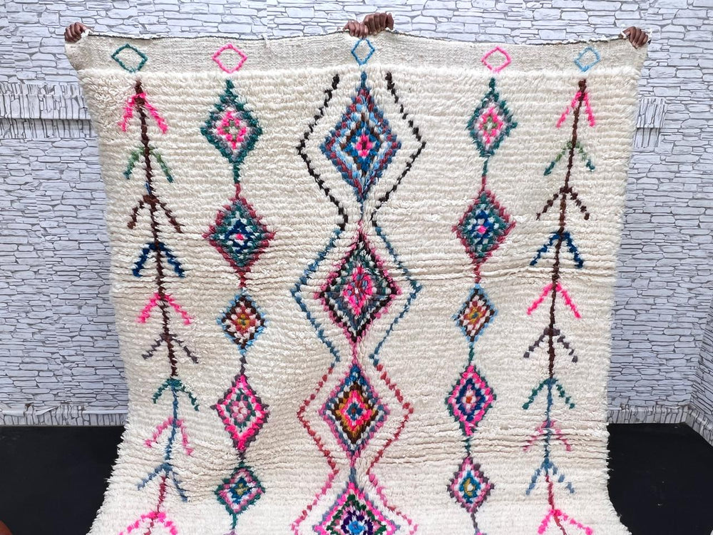Colorful handmade Moroccan Berber rug with diamond tribal patterns on white wool