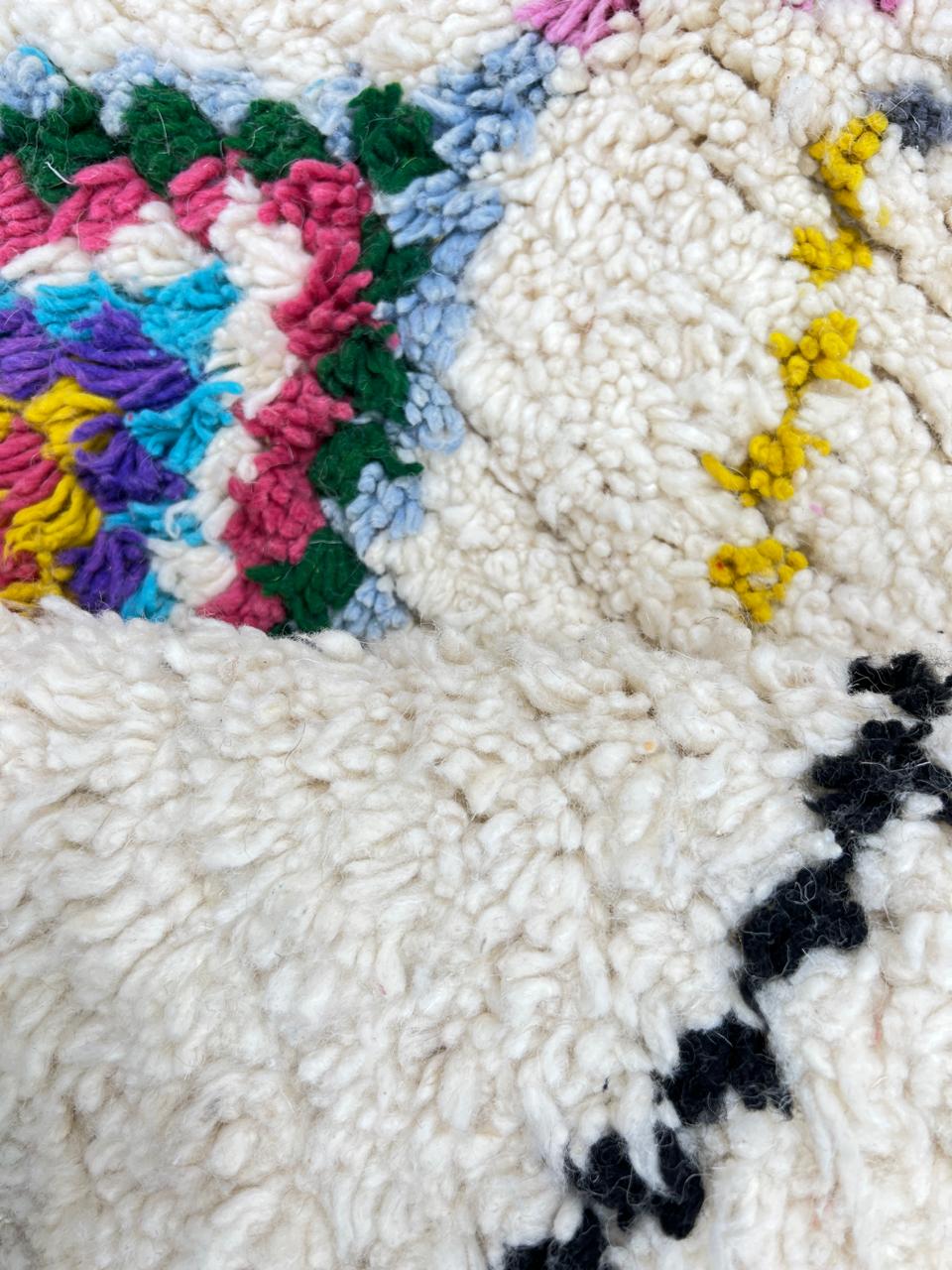 Colorful handmade Moroccan Berber wool rug with vibrant diamond patterns on ivory background