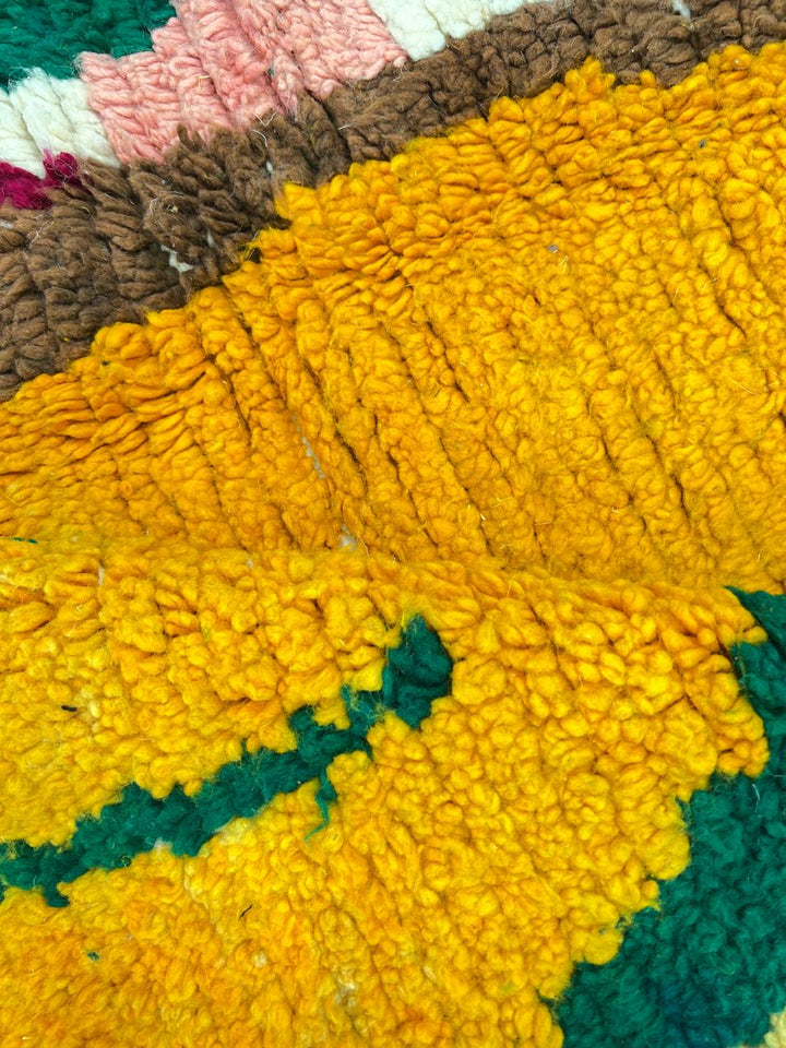 Handwoven colorful Moroccan wool rug with abstract geometric design in pink, yellow, green, and black tones