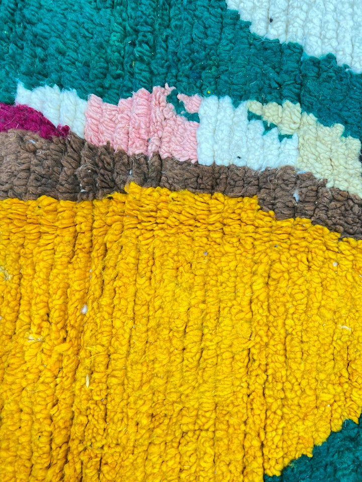 Colorful abstract Moroccan round rug with mustard, green, pink, and black geometric art pattern.