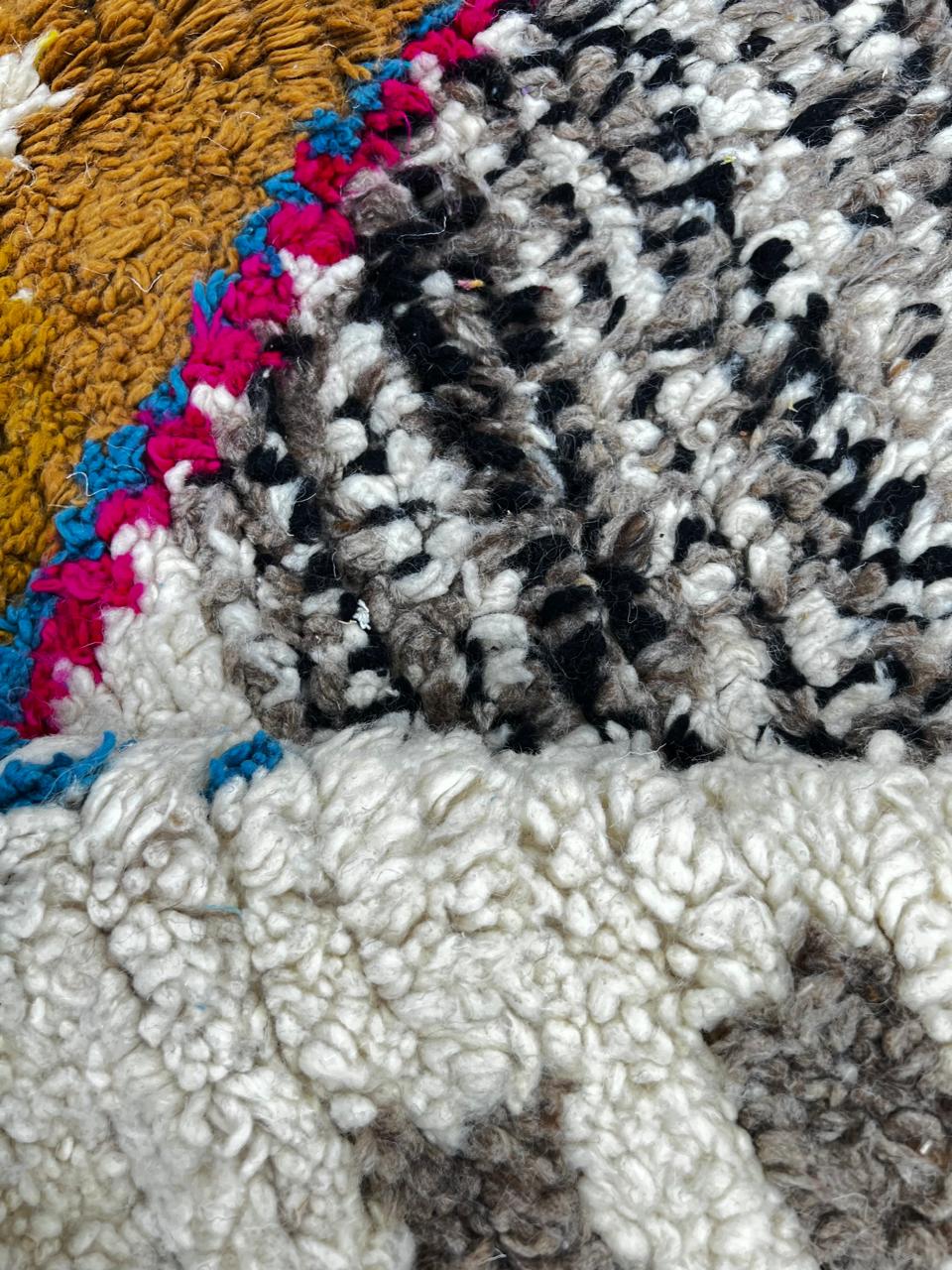 Handmade colorful Moroccan wool runner rug with geometric tribal patterns in pink, yellow, blue, green, and black on a white base.