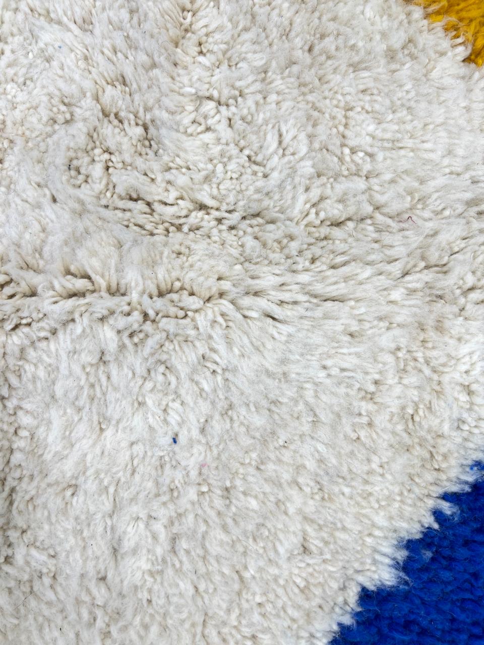 Colorful geometric Moroccan wool runner rug with abstract shapes in pink, blue, green, and yellow on a cream base
