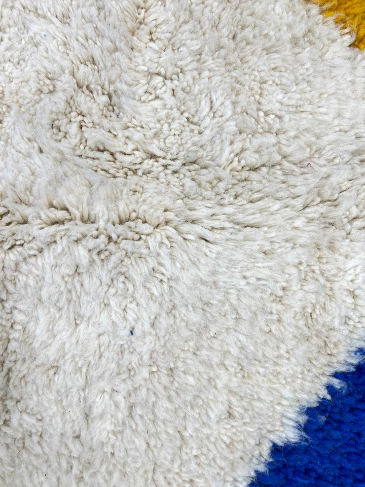 Colorful geometric Moroccan wool runner rug with abstract shapes in pink, blue, green, and yellow on a cream base