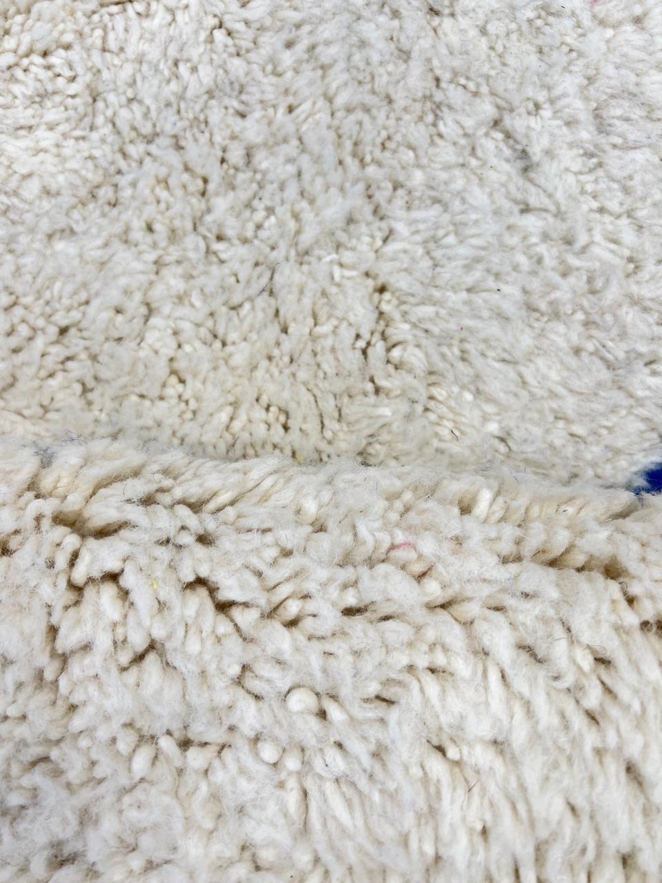 Colorful geometric Moroccan wool runner rug with abstract shapes in pink, blue, green, and yellow on a cream base