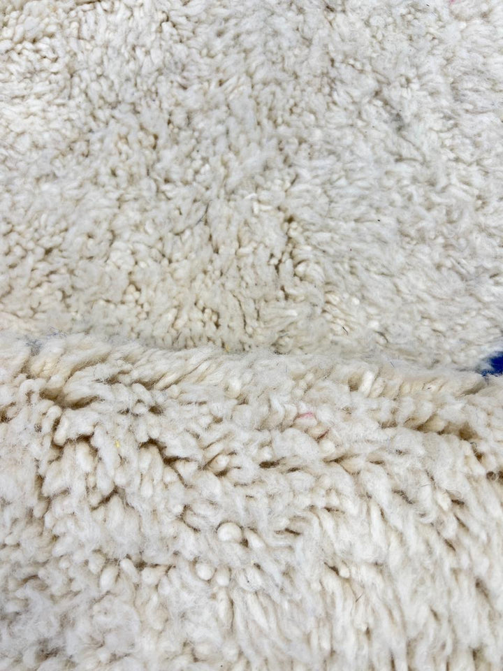 Colorful geometric Moroccan wool runner rug with abstract shapes in pink, blue, green, and yellow on a cream base