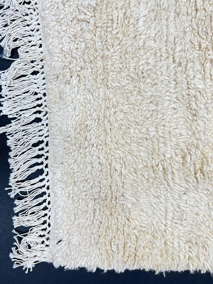 Cream handmade Moroccan wool rug with soft plush texture and fringed edges