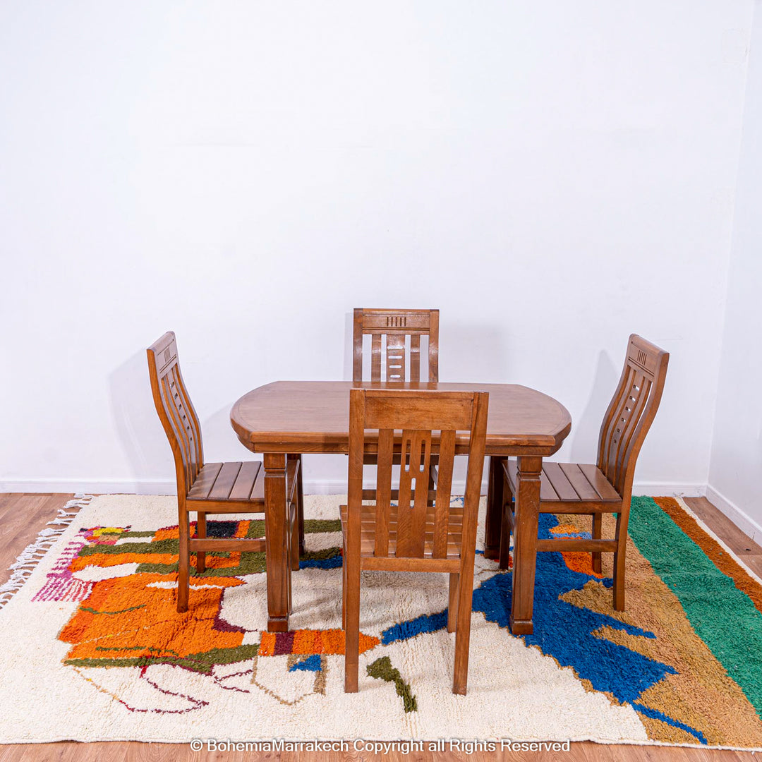 Colorful Moroccan rug featuring abstract camel design under a wooden dining set, handcrafted by Berber artisans.
