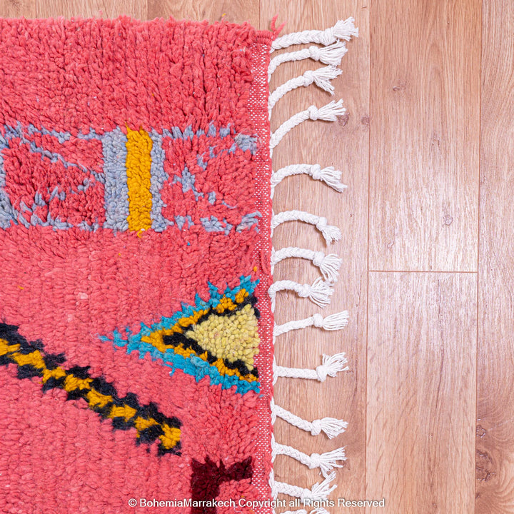 Colorful bright pink Moroccan wool rug with blue and yellow diamond patterns