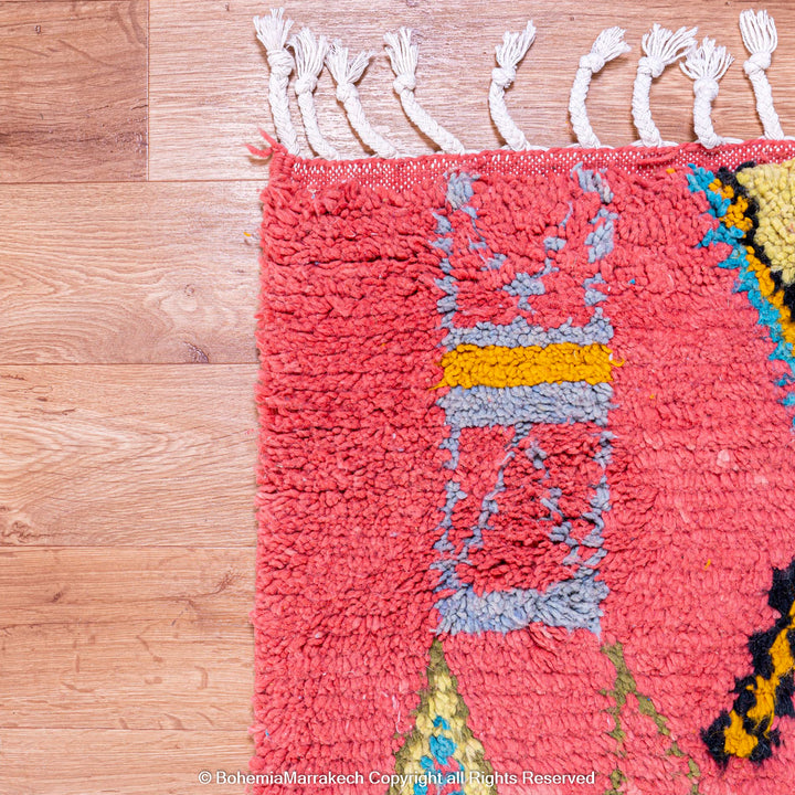 Colorful bright pink Moroccan wool rug with blue and yellow diamond patterns