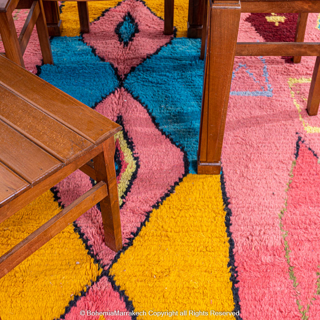 Colorful bright pink Moroccan wool rug with blue and yellow diamond patterns