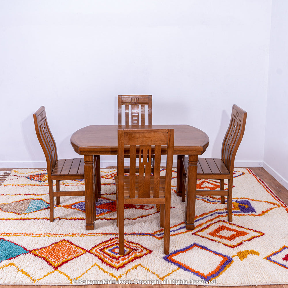 Handmade colorful Moroccan rug with bold tribal diamond pattern in orange, blue, red, and yellow on natural wool background