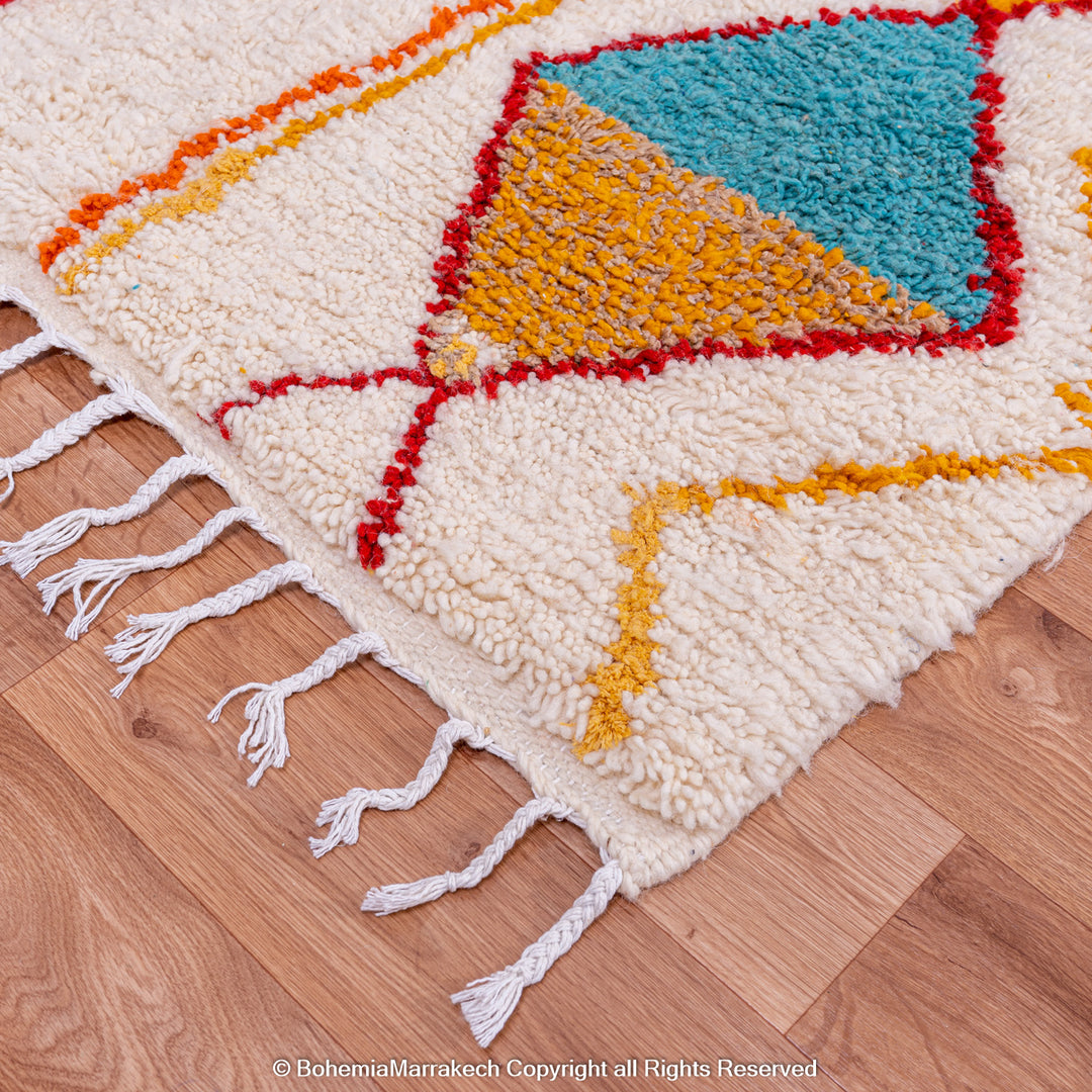 Handmade colorful Moroccan rug with bold tribal diamond pattern in orange, blue, red, and yellow on natural wool background