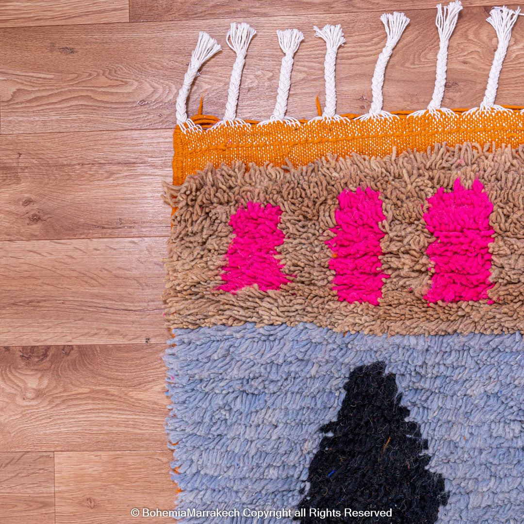 Colorful Moroccan wool rug with geometric shapes, featuring pink, blue, and black motifs. Handmade by Berber women. Moroccan carpet.