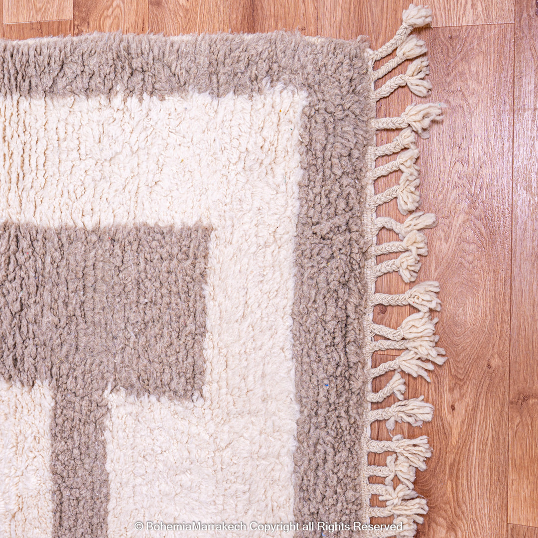 Minimalist Moroccan wool rug with beige border design on cream background