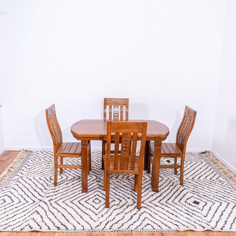 White Moroccan rug with black diamond lines under wooden dining set, handwoven wool, traditional Berber style, area rug for sale.