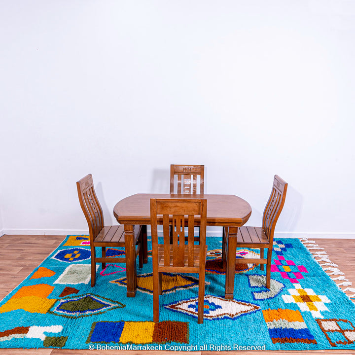 Colorful blue Moroccan Berber rug with a wooden dining set, featuring geometric patterns and traditional Amazigh designs.
