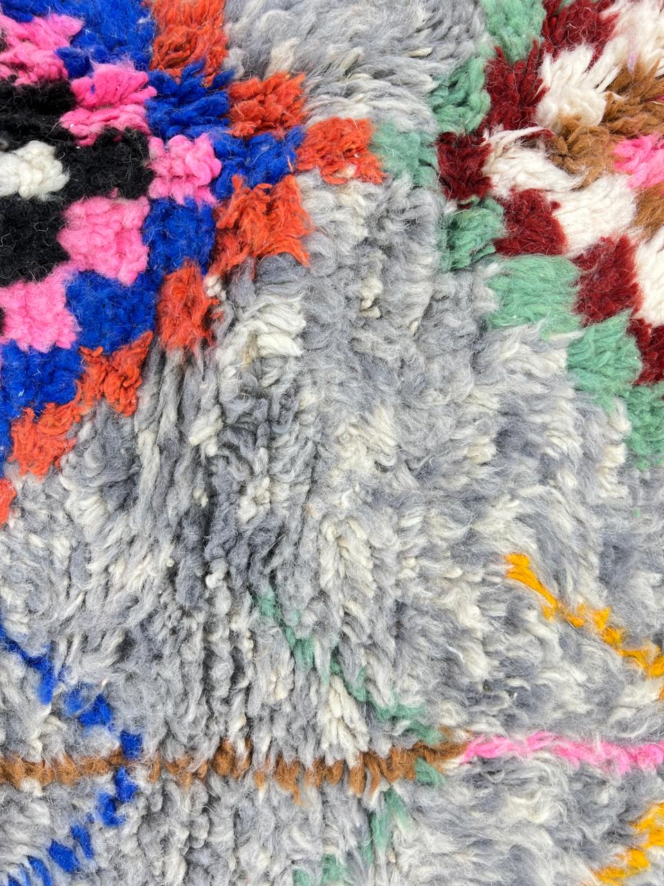 Round grey Moroccan wool rug with colorful Berber diamond motifs and tribal geometric patterns.