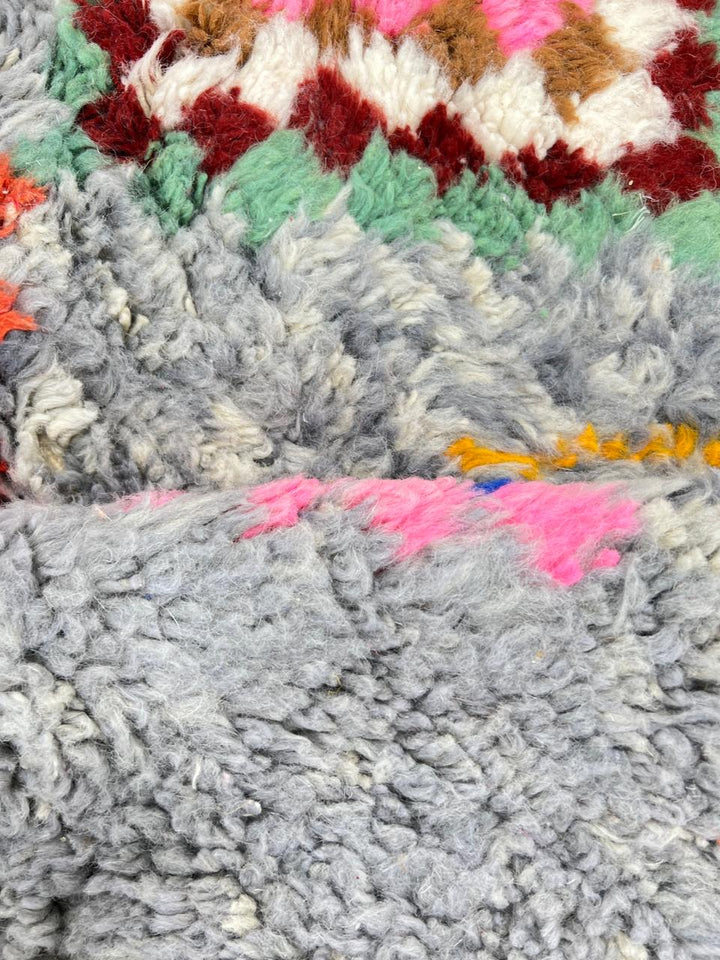 Round grey Moroccan wool rug with colorful Berber diamond motifs and tribal geometric patterns.