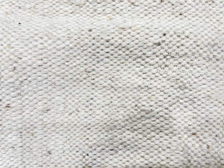 Handmade Moroccan flatweave kilim rug with soft neutral tones and subtle geometric shapes, woven from natural wool.