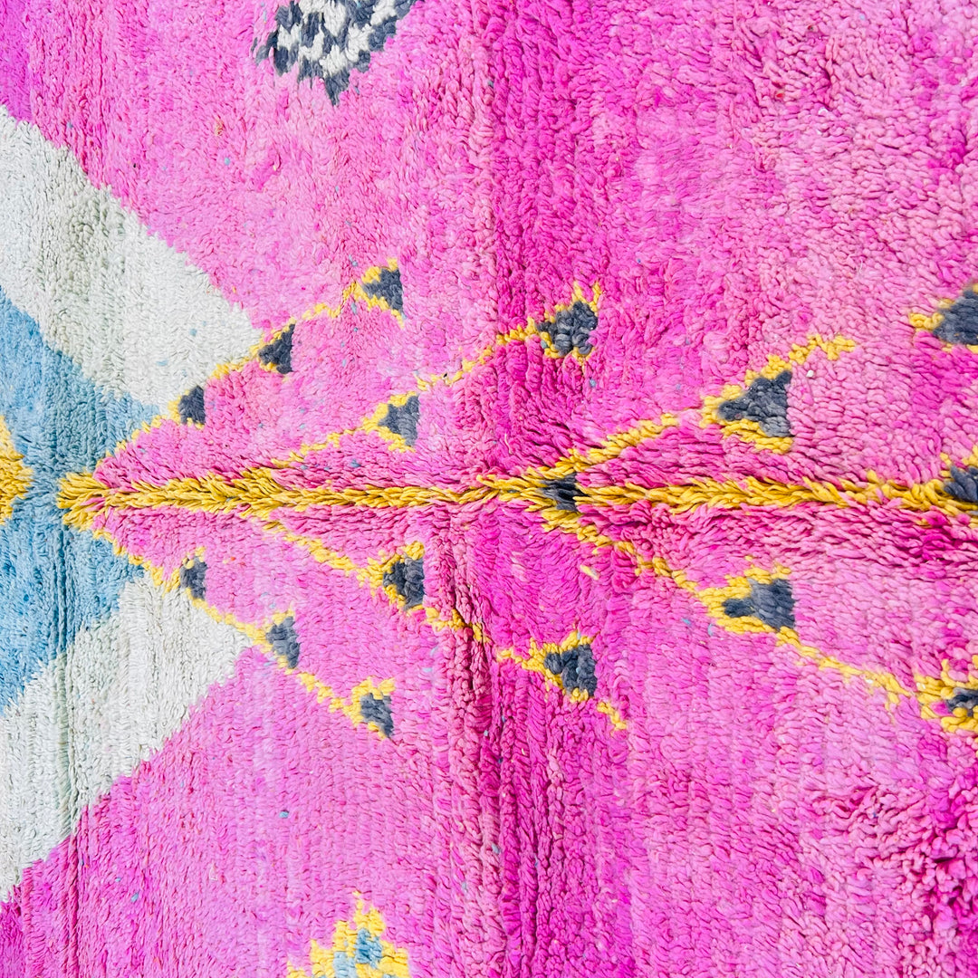 Vintage Moroccan rug with pink, yellow, and blue geometric patterns, 100% wool, handwoven in the Atlas Mountains; stunning artistry.