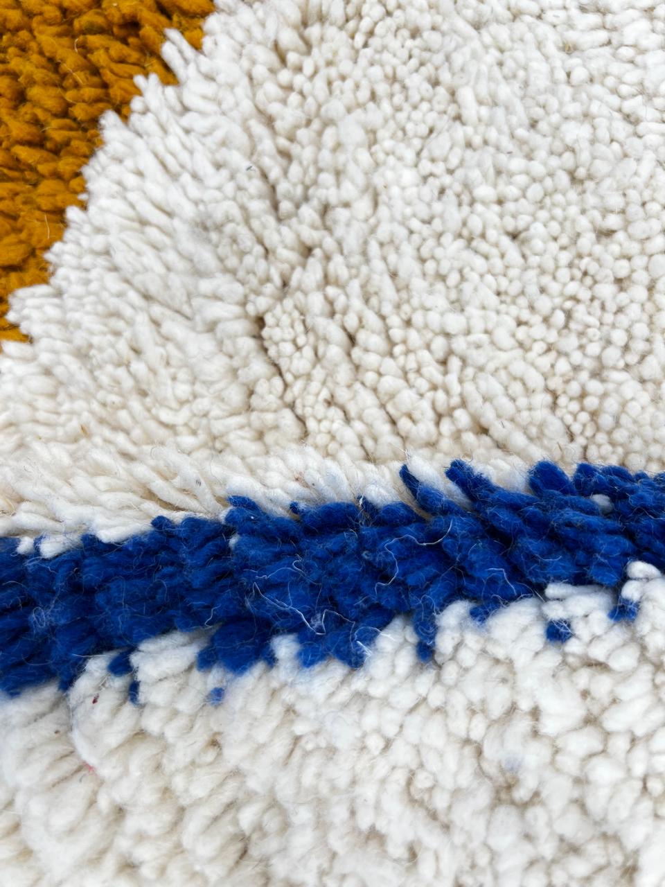 Handwoven ivory Moroccan wool rug with blue, amber, and olive geometric Berber designs