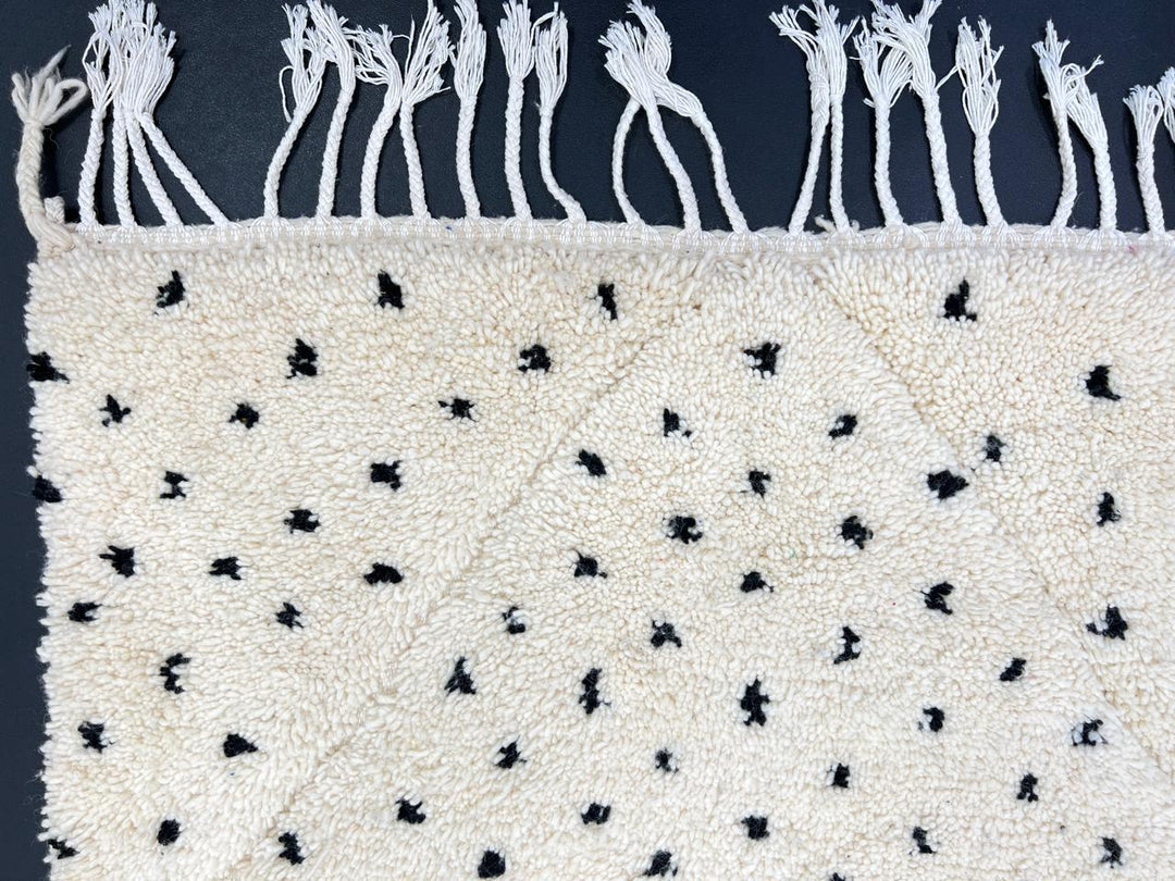 Handwoven Moroccan wool rug with small black dotted patterns on an ivory background, minimalist Beni Ourain design