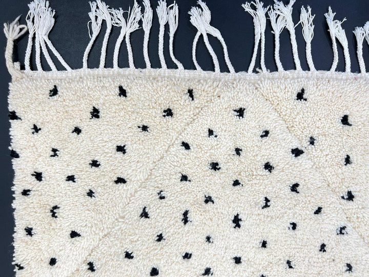 Handwoven Moroccan wool rug with small black dotted patterns on an ivory background, minimalist Beni Ourain design
