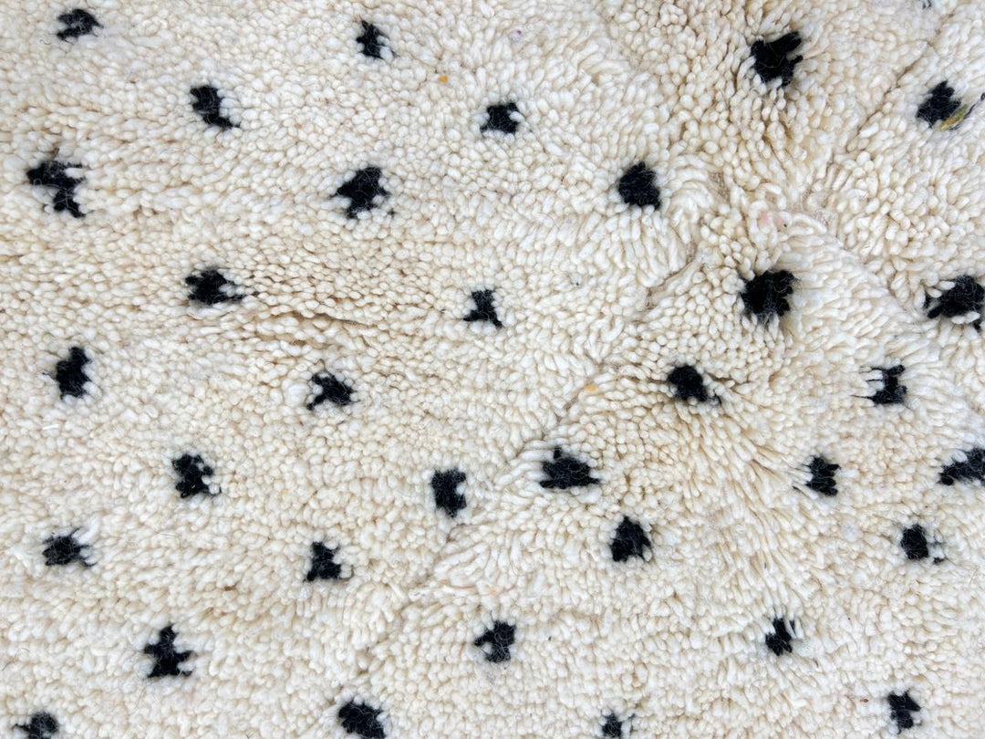 Handwoven Moroccan wool rug with small black dotted patterns on an ivory background, minimalist Beni Ourain design