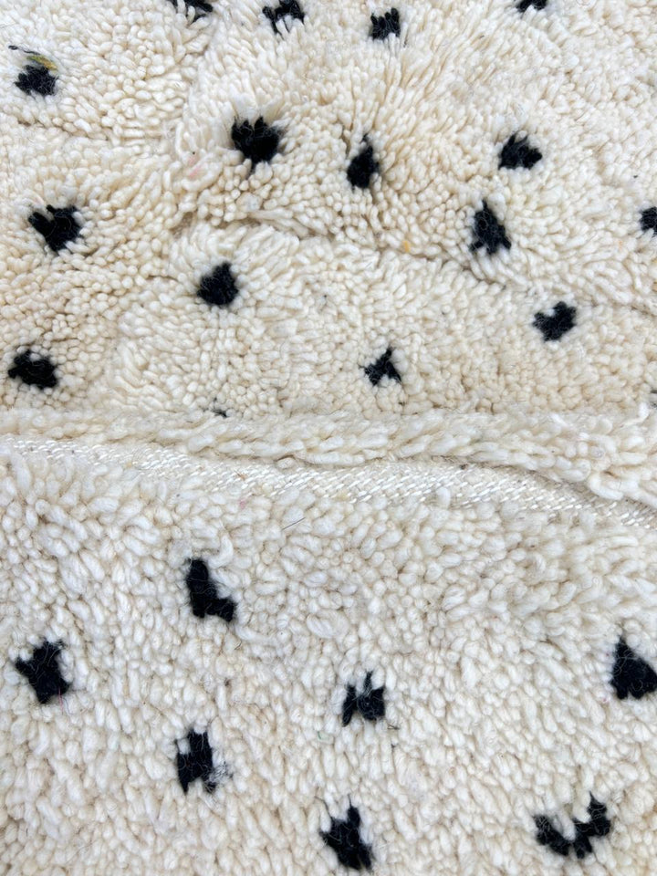 Handwoven Moroccan wool rug with small black dotted patterns on an ivory background, minimalist Beni Ourain design