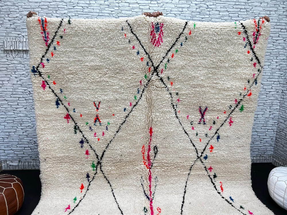 Minimalist Moroccan wool rug with black diamond lines and colorful details on cream background, handmade by Berber artisans