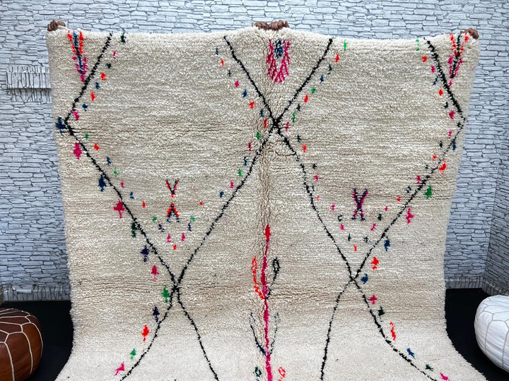 Minimalist Moroccan wool rug with black diamond lines and colorful details on cream background, handmade by Berber artisans