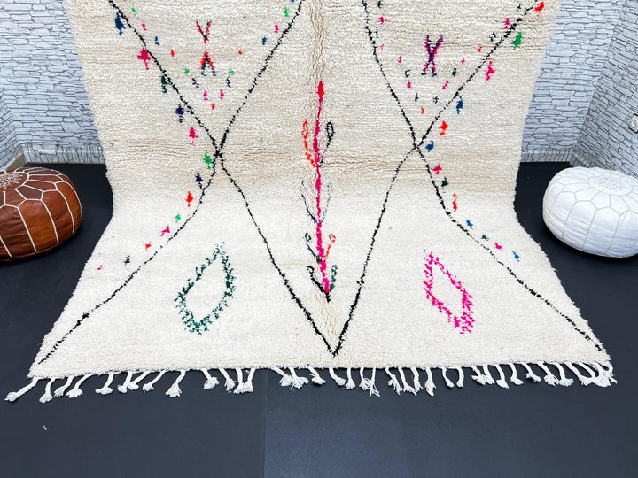 Minimalist Moroccan wool rug with black diamond lines and colorful details on cream background, handmade by Berber artisans