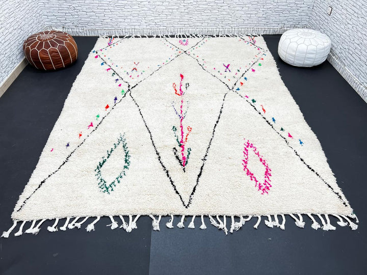 Minimalist Moroccan wool rug with black diamond lines and colorful details on cream background, handmade by Berber artisans