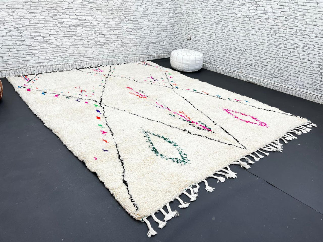 Minimalist Moroccan wool rug with black diamond lines and colorful details on cream background, handmade by Berber artisans