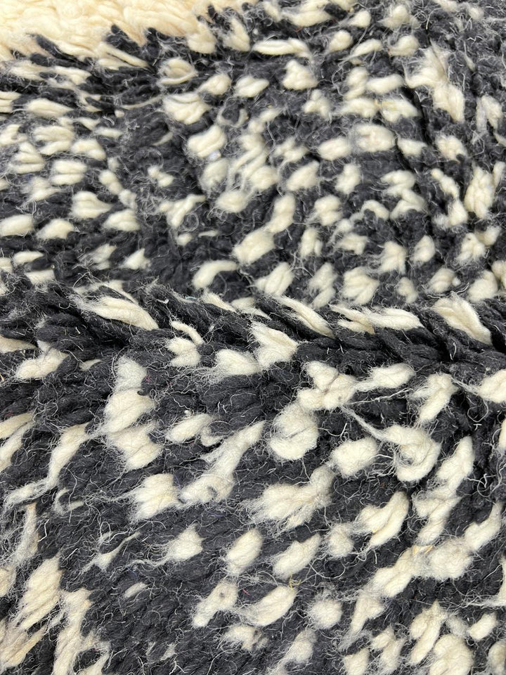 Round modern Moroccan rug with abstract black, white, and red textured pattern.