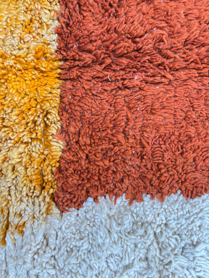 Handmade Moroccan runner rug with colorful abstract geometric shapes in blue, pink, and orange on a white wool background.