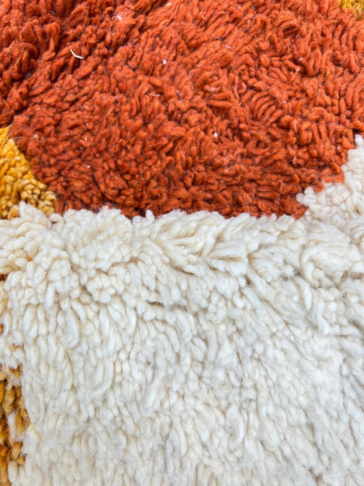 Handmade Moroccan runner rug with colorful abstract geometric shapes in blue, pink, and orange on a white wool background.