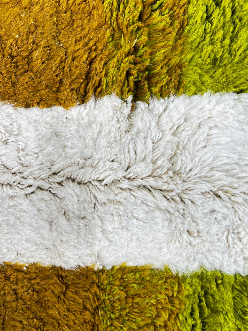 Handmade modern abstract Moroccan wool runner rug with geometric black, green, yellow, and pink design on a white background