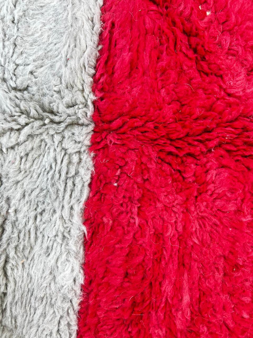 Round handmade Moroccan wool rug with a bold abstract geometric design in burnt orange, ivory, gray, red, yellow, and black.