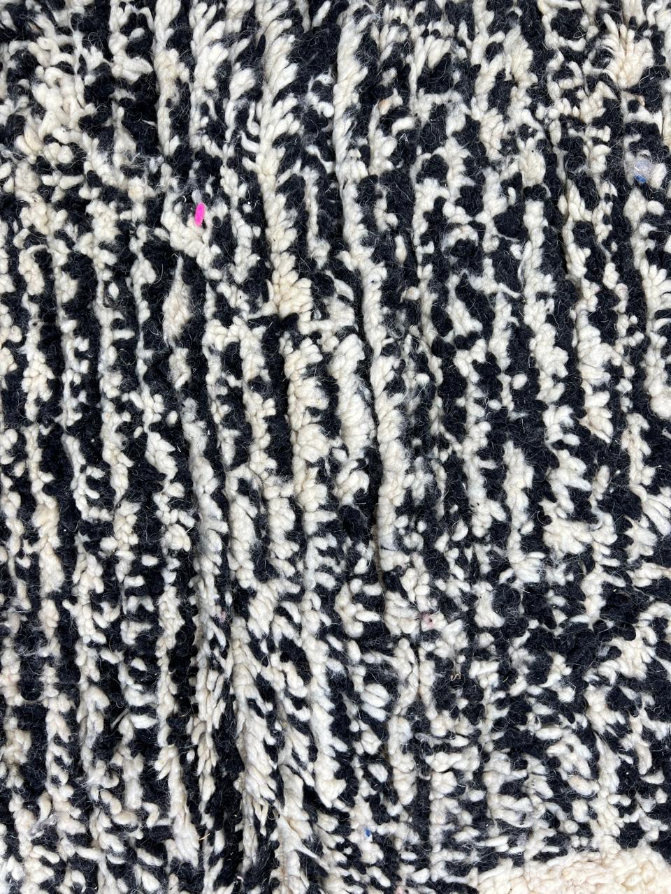 Round modern Moroccan rug with abstract pink, red, black, and white pattern.