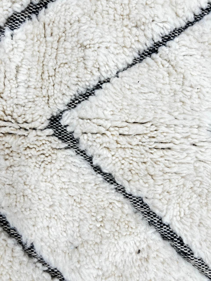 Modern Moroccan Beni Ourain wool rug with black chevron lines on cream background, handmade by Berber artisans